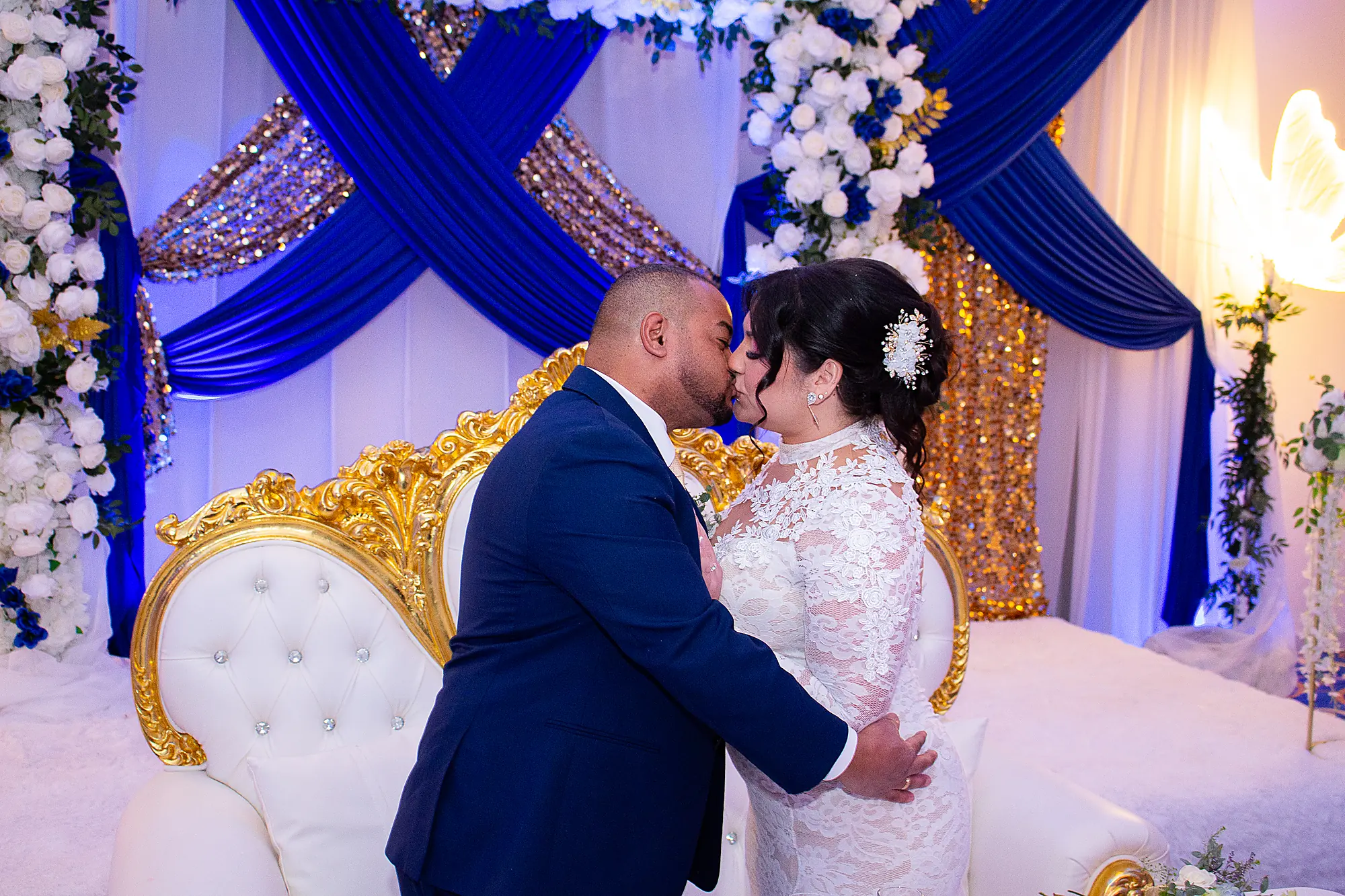 Bride and groom kissing at their reception, blue and gold decor