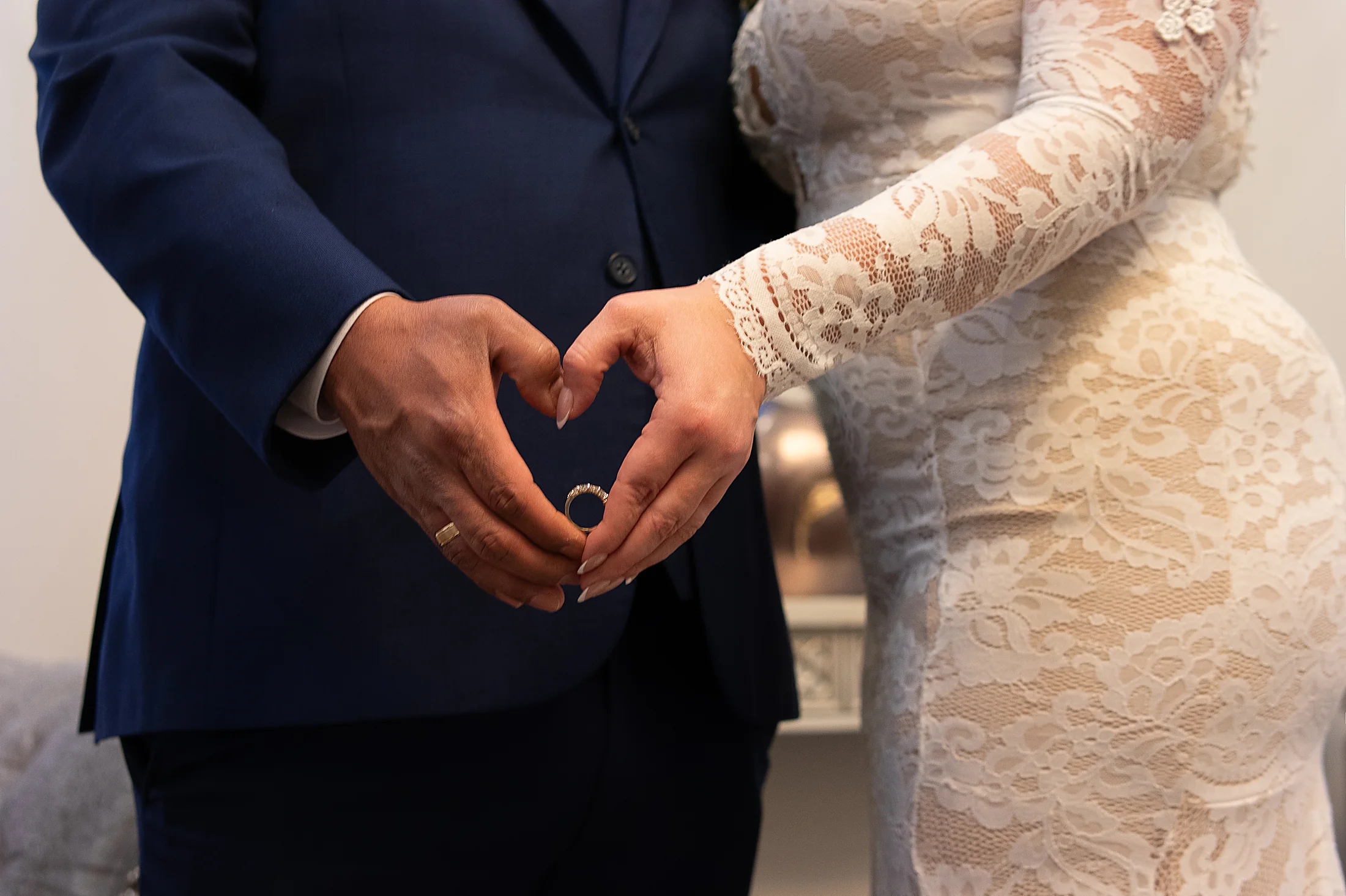 Bride and groom's hands forming a heart around the wedding ring
