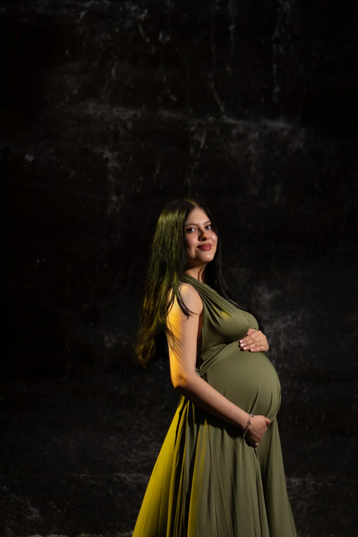 Pregnant woman in a flowing olive green gown